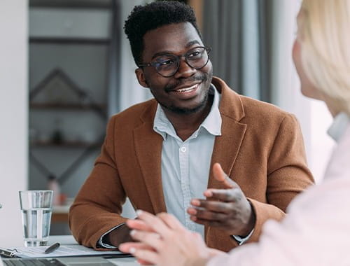 young man glasses brown jacket blazer student meeting woman blond hair laptop office meeting room