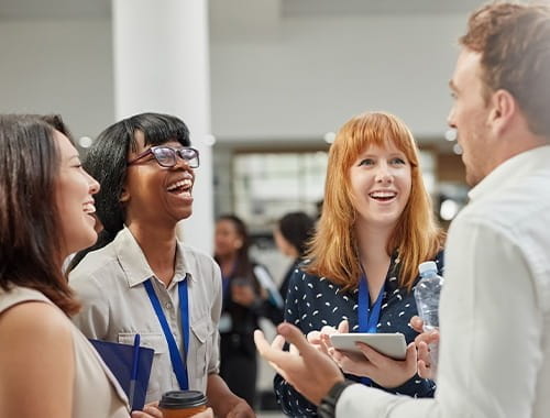 students standing in a group laughing talking lanyards ID London Student Society