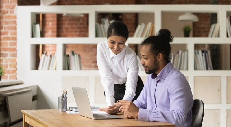 Smiling Indian businesswoman mentor training African American intern in office