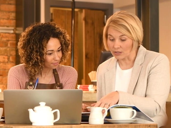 Two women working over a coffee