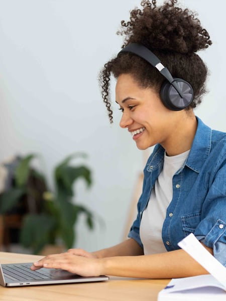 Woman with laptop open and headphones.